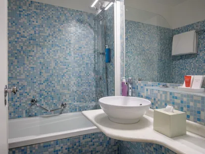 Bagno a mosaico con vasca e lavabo in marmo