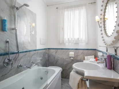 Bagno con vasca e rivestimento grigio della camera Doppia Executive