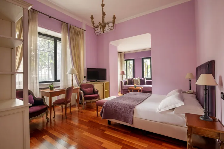 Junior Suite del Fenix Hotel Roma nei toni del viola, con letto matrimoniale e zona salotto