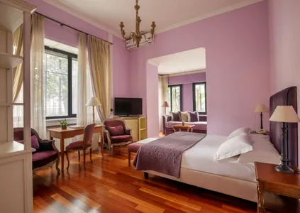 Junior Suite del Fenix Hotel Roma nei toni del viola, con letto matrimoniale e zona salotto