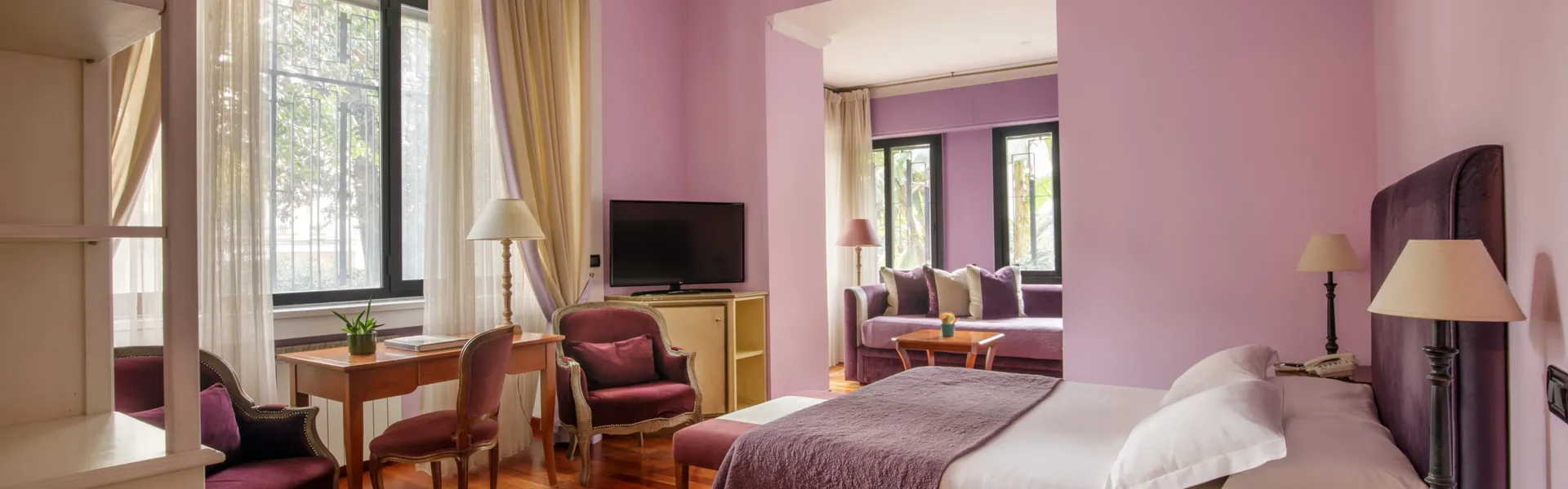 Junior Suite del Fenix Hotel Roma nei toni del viola, con letto matrimoniale e zona salotto