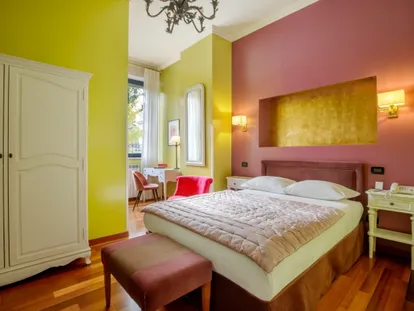 Junior Suite con pareti gialle e rosa e nicchia dorata sopra il letto